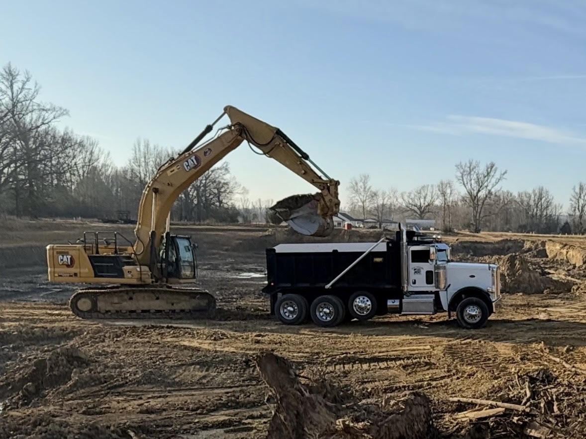 CAT excavator loading a Peterbilt dump truck on a C&C Dirt Contractors job site